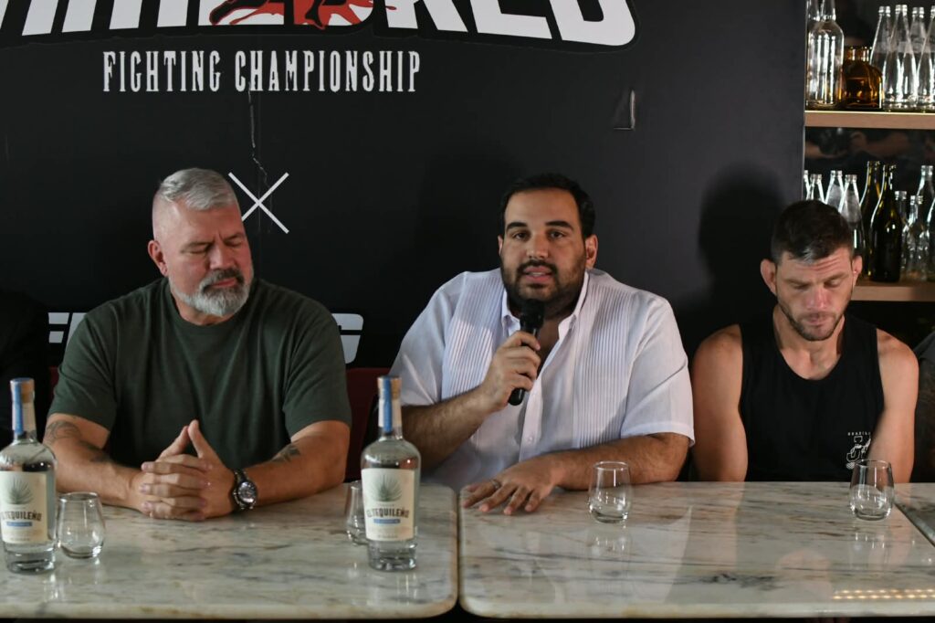 Rodolfo Dauhajre, junto a Lex McMahon y uno de los atletas, ofrece detalles en la rueda de prensa.